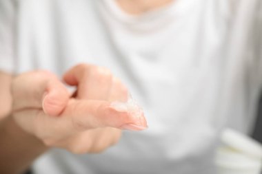 Woman with sample of cosmetic petrolatum on her finger, closeup. Space for text clipart