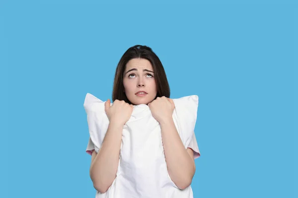 明るい青の背景に枕を持つ不幸な若い女性 不眠症の問題 — ストック写真