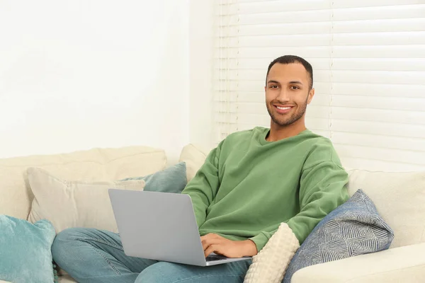 笑顔アフリカ系アメリカ人男性とともにラップトップ上のソファで部屋 — ストック写真