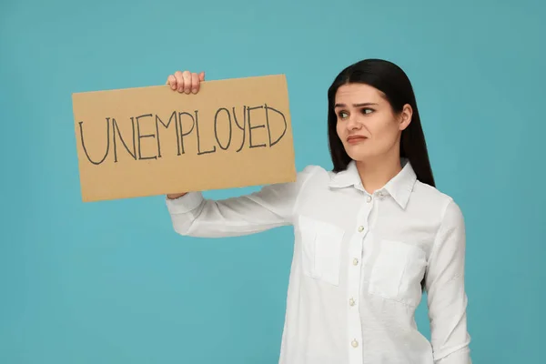 拿着写着字的不快乐女人浅蓝色背景的失业 — 图库照片
