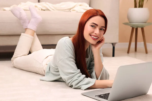 家中笔记本电脑旁的地板上躺着红头发的快乐女人 — 图库照片