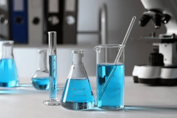 Verschillende Laboratoriumglaswerk Met Lichtblauwe Vloeistof Tafel — Stockfoto