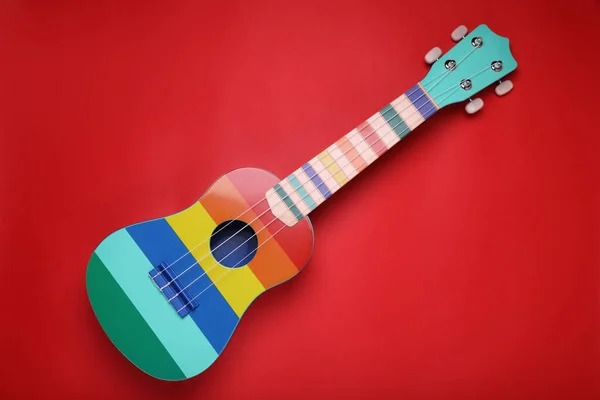 Kleurrijke Ukelele Rode Achtergrond Bovenaanzicht Strijkmuziekinstrument — Stockfoto