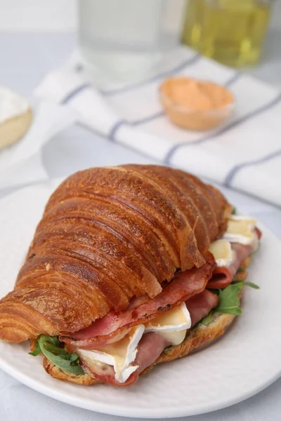 stock image Tasty croissant with brie cheese, ham and bacon on white table, closeup