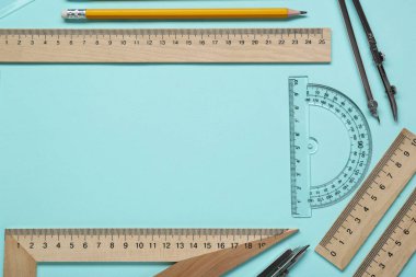 Turkuaz arka planda farklı cetvel ve açıölçer içeren düz kompozisyon. Metin için boşluk