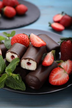 Lezzetli kremalı atıştırmalıklar taze çilekler ve açık mavi ahşap masada nane şekeri.