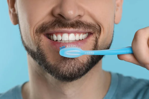Mann Beim Zähneputzen Mit Plastikzahnbürste Auf Hellblauem Hintergrund Nahaufnahme — Stockfoto