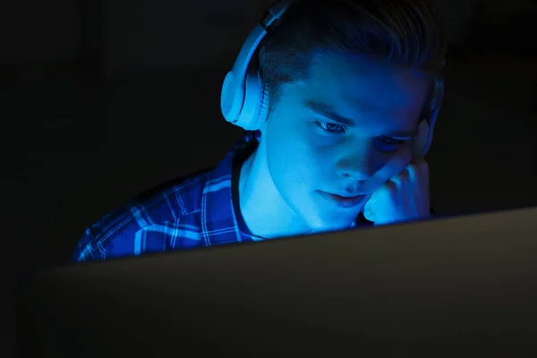 十几岁的男孩晚上用电脑在耳机里 上网成瘾 — 图库照片