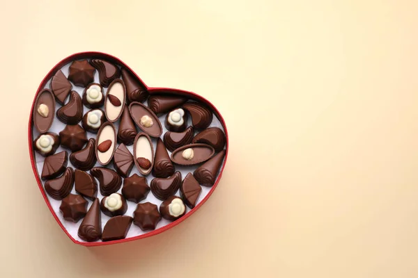 Hartvormige Doos Met Heerlijke Chocolade Snoepjes Beige Achtergrond Bovenaanzicht Ruimte — Stockfoto