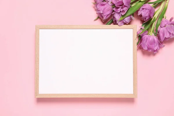 stock image Empty photo frame and beautiful flowers on pink background, flat lay. Space for design