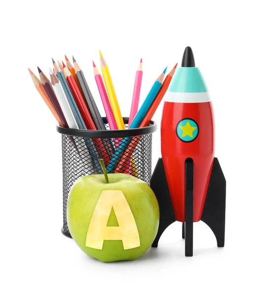 Apple with carved letter A as school grade. Bright toy rocket and pencils on white background