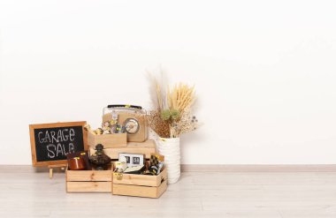 Sign Garage Sale written on blackboard near many different stuff indoors. Space for text