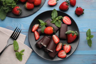 Lezzetli kremalı aperatifler taze çilek ve açık mavi ahşap masa üzerinde nane, düz uzanmış