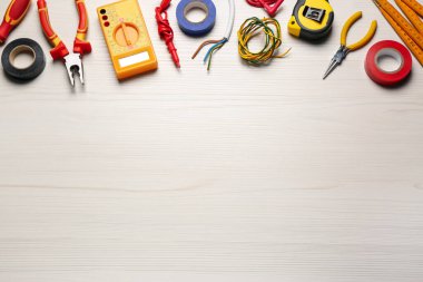 Beyaz ahşap masa üzerinde farklı kablolar ve elektrikçilerin aletleri düz yerde. Metin için boşluk