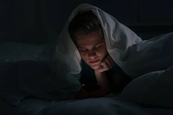 Мальчик Подросток Использует Смартфон Одеялом Кровати Ночью Интернет Зависимость — стоковое фото
