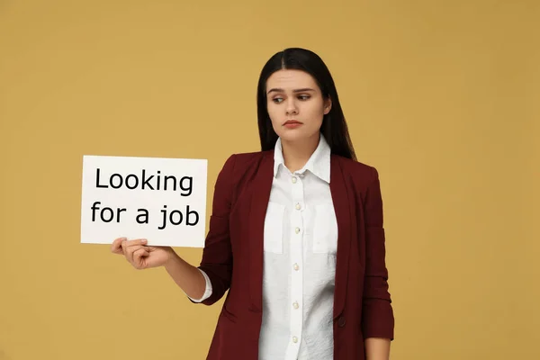 失业问题 不快乐的女人拿着标语牌 带着浅橙色背景的求职标语 — 图库照片