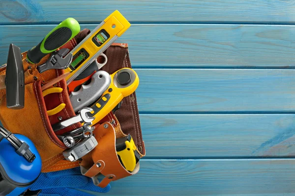 Açık mavi ahşap masa üzerinde farklı aletleri olan kemer, üst görüş. Metin için boşluk