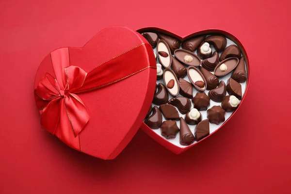 Hjärtformad Låda Med Läckra Choklad Godis Röd Bakgrund Ovanifrån — Stockfoto