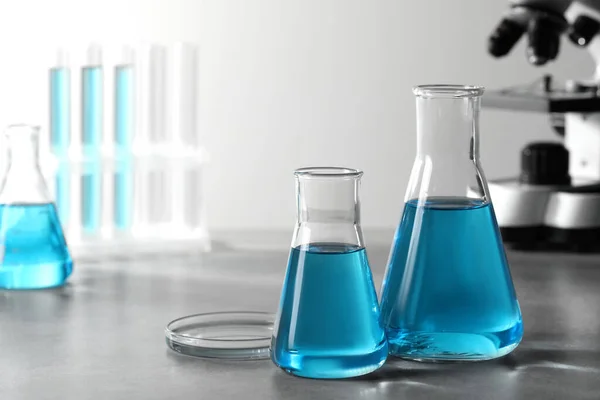 Verschillende Laboratoriumglaswerk Met Lichtblauwe Vloeistof Tafel Ruimte Voor Tekst — Stockfoto