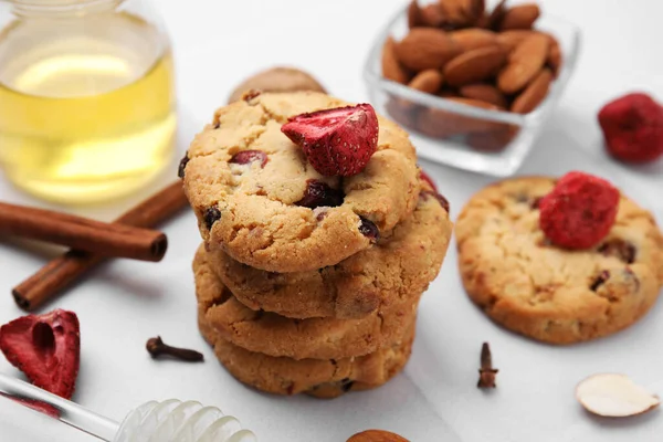 Cookies with freeze dried fruits, cinnamon, honey and nuts on white tiled table, closeup