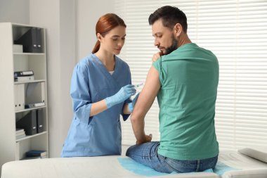 Doktor klinikteki hastaya hepatit aşısı veriyor.