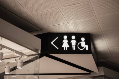 Semboller ve oklar umumi tuvaletin yakınındaki alışveriş merkezinde siyah tabelanın üzerinde