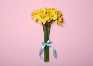 Pembe arka planda sarı nergis buketi.