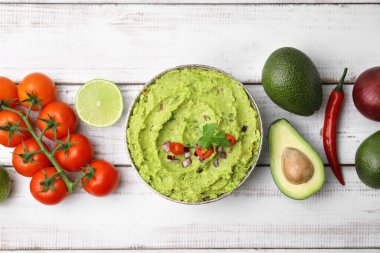 Bir kase lezzetli guacamole ve malzemeler beyaz ahşap masada, düz yerde.