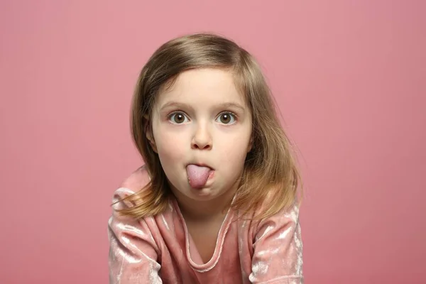 Lustiges Kleines Mädchen Zeigt Ihre Zunge Auf Rosa Hintergrund — Stockfoto