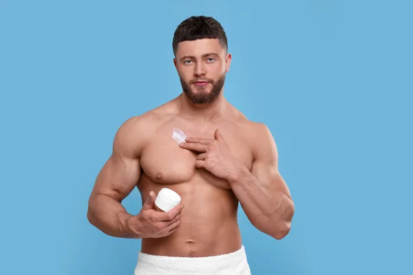 Knappe Man Het Aanbrengen Van Body Cream Zijn Borst Lichtblauwe — Stockfoto