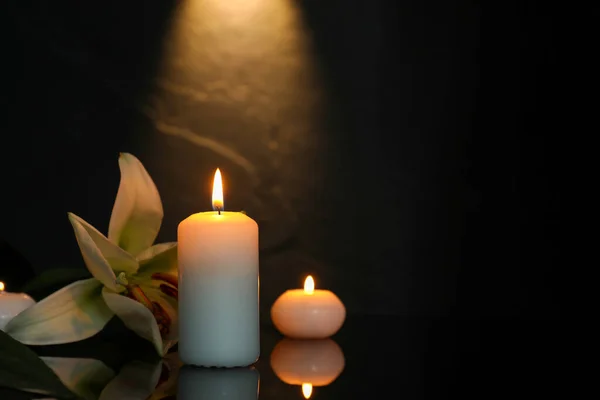 白百合和燃烧的蜡烛在黑暗的黑色镜子表面 文字的空间 丧葬标志 — 图库照片