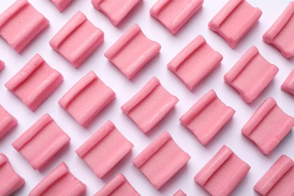 Tasty pink chewing gums on white background, flat lay