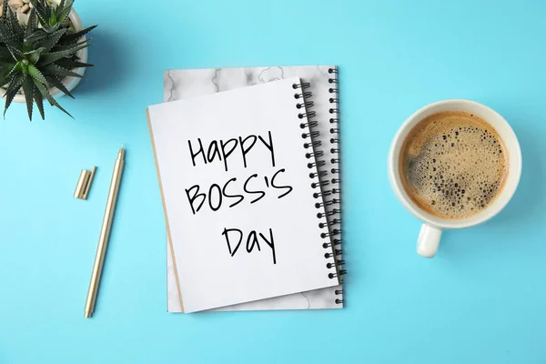 Notebook with phrase Happy Boss`s Day, coffee and plant on light blue table, flat lay