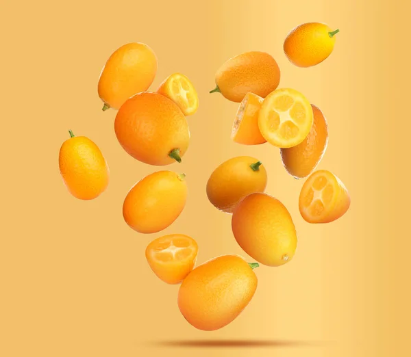 Delicious Whole Cut Kumquats Falling Pale Orange Background — Stock Photo, Image