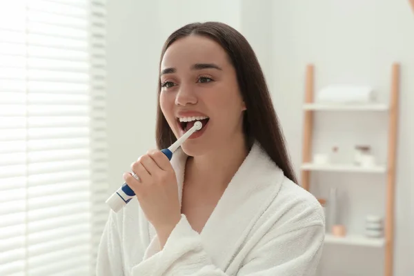 Młoda Kobieta Myje Zęby Elektryczną Szczoteczką Zębów Łazience — Zdjęcie stockowe