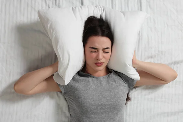 Irritated Young Woman Covering Her Ears Pillow Bed Top View — Stock Photo, Image