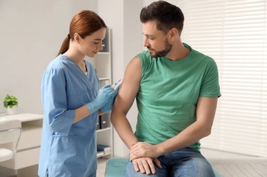 Doktor klinikteki hastaya hepatit aşısı veriyor.