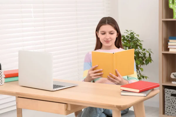 Odada Dizüstü Bilgisayarın Yanında Kitap Okuyan Tatlı Bir Kız Işyeri — Stok fotoğraf