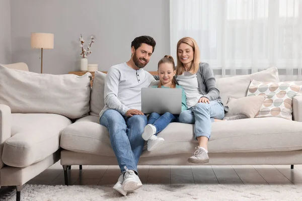 Happy family with laptop on sofa at home