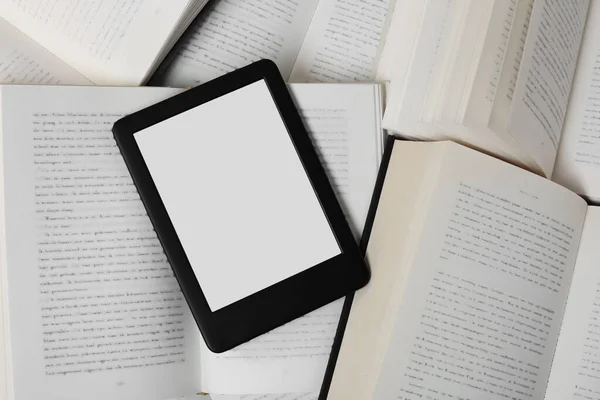 Portable e-book reader on different open books, top view