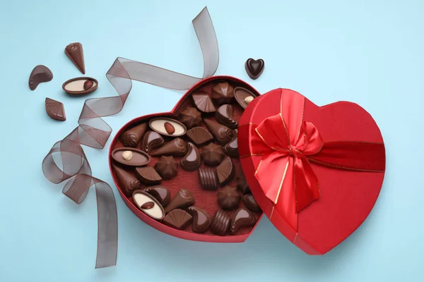 Hartvormige Doos Met Heerlijke Chocolade Snoepjes Lint Lichtblauwe Ondergrond Plat — Stockfoto