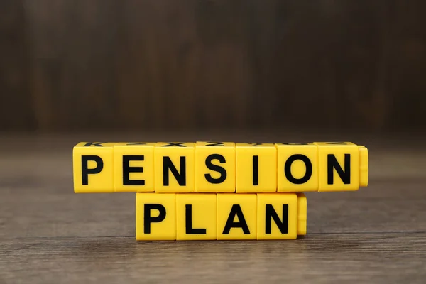 Words Pension Plan made of yellow cubes on wooden table, closeup