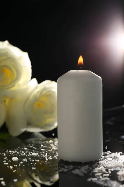 白色的玫瑰和燃烧的蜡烛在黑色的镜子表面在黑暗中 丧葬标志 — 图库照片