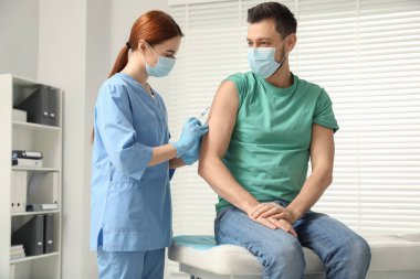 Doktor klinikteki hastaya hepatit aşısı veriyor.