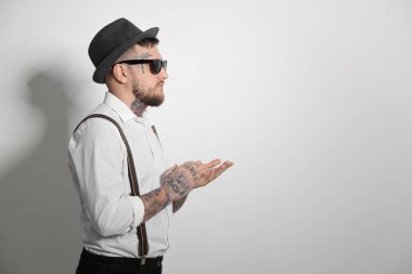 Handsome hipster man wearing stylish sunglasses on light grey background. Space for text