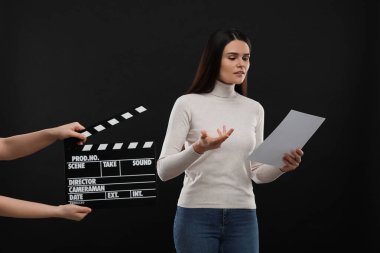 Aktris sahnedeyken ikinci asistan kamera siyah arka planda el çırpma tahtası tutuyor. Film endüstrisi
