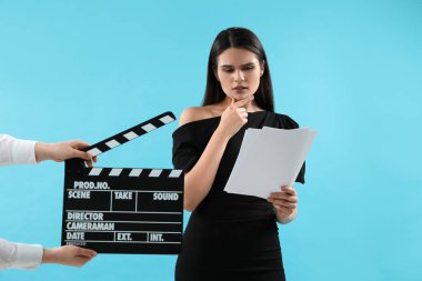Aktris rolünü oynarken ikinci asistan kamera açık mavi arka planda el çırpma tahtası tutuyor. Film endüstrisi