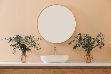 Stylish mirror, eucalyptus branches and vessel sink in modern bathroom. Interior design