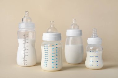 Feeding bottles with baby formula on beige background