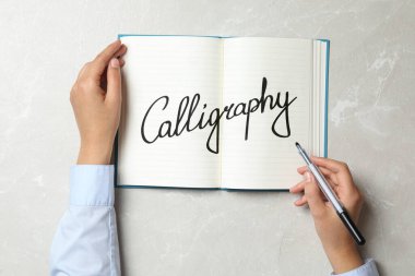 Not defterine yazı yazan kadın mermer masa, üst görünüm